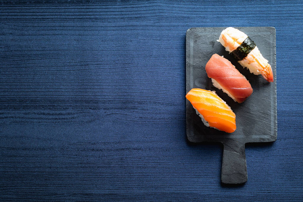 Elegant sushi on wood table. Some Nigiri, with soy sauce and chopstick - Photo, Image