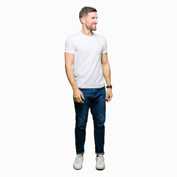 Handsome man wearing casual white t-shirt looking away to side with smile on face, natural expression. Laughing confident. - Fotografie, Obrázek