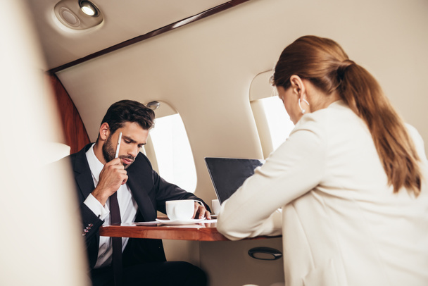 selective focus of businessman and businesswoman working in private plane  - Foto, Imagem