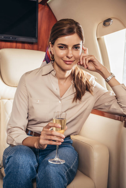 atractiva mujer en camisa sosteniendo copa de champán en avión privado
  - Foto, imagen