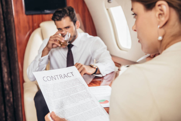 selectieve focus van zakenvrouw met een contract in een privaat vliegtuig  - Foto, afbeelding