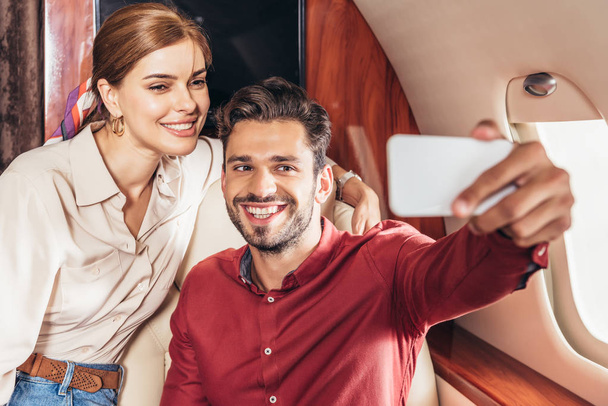selective focus of boyfriend and girlfriend talking selfie in private plane  - Fotografie, Obrázek