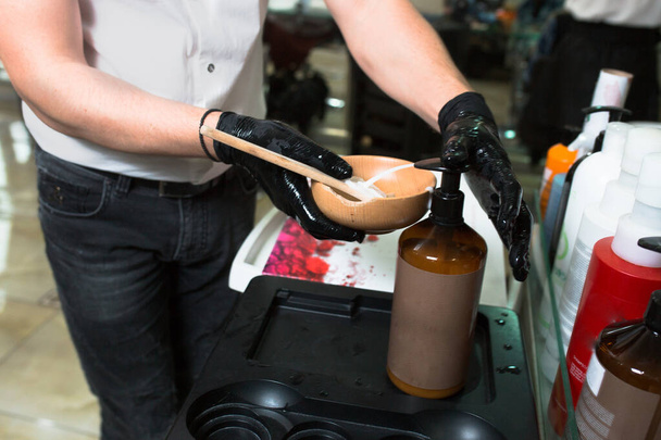Male Stylist in gloves preparing color cream for dying hair cont - Photo, Image