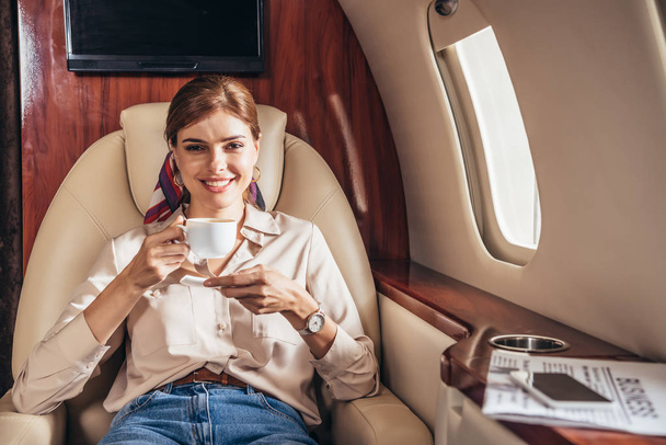 femme souriante en chemise tenant tasse de café dans un avion privé
  - Photo, image