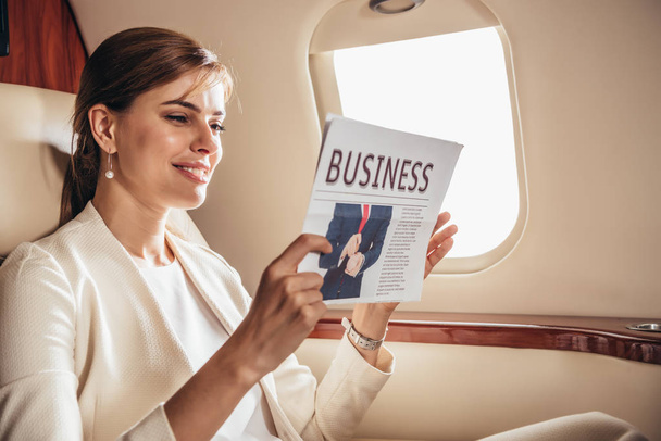 atrakcyjna bizneswoman w garniturze pisząca gazety w prywatnym samolocie  - Zdjęcie, obraz