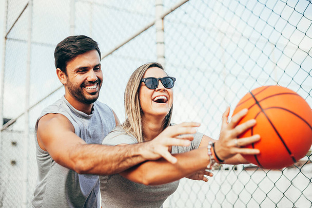 Summer vacation, sport, games and friendship concept - happy couple playing basketball outdoors - 写真・画像