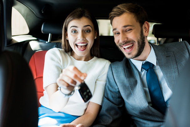 selective focus of excited woman holding car key near handsome man in suit  - Фото, изображение