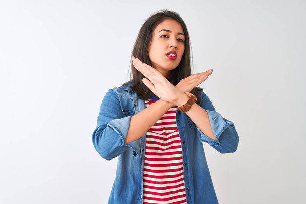 Young chinese woman wearing striped t-shirt and denim shirt over isolated white background Rejection expression crossing arms doing negative sign, angry face - Фото, зображення