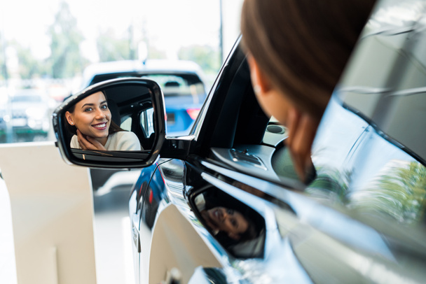 selective focus of happy woman looking at car mirror  - Photo, Image