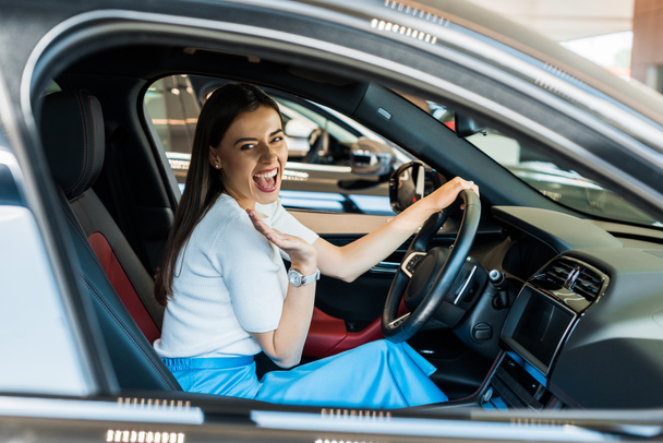 enfoque selectivo de la mujer emocionada agitando la mano mientras está sentado en el coche
  - Foto, Imagen