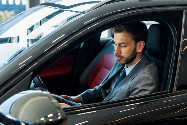 selective focus of handsome bearded man sitting on modern car  - Zdjęcie, obraz