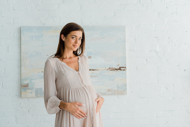 happy pregnant woman touching her belly at home - Photo, Image