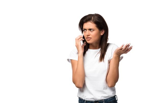 verwarde jonge vrouw praten op smartphone, geïsoleerd op wit - Foto, afbeelding