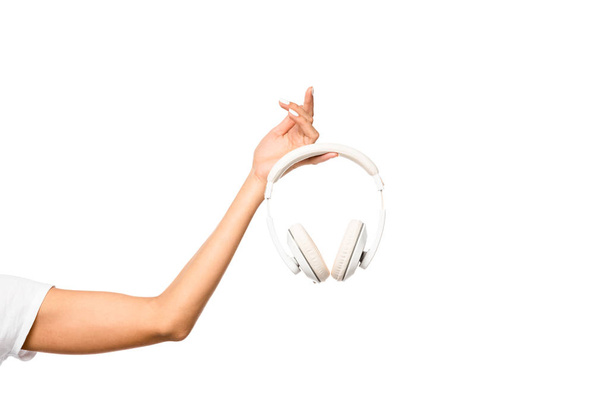 oříznutý pohled mladé ženy držící sluchátka, izolovaná na bílém - Fotografie, Obrázek