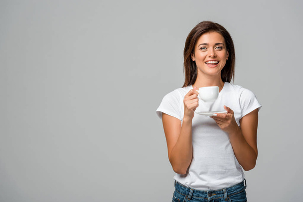 beautiful smiling woman holding cup of coffee, isolated on grey - 写真・画像