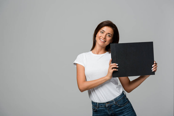 beautiful happy woman holding empty black board, isolated on grey  - Фото, зображення