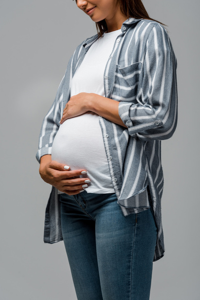 vista cortada da bela mulher grávida tocando barriga isolada no cinza
 - Foto, Imagem