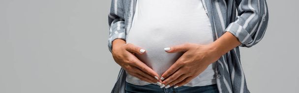 partial view of pregnant woman touching tummy isolated on grey - Foto, Bild
