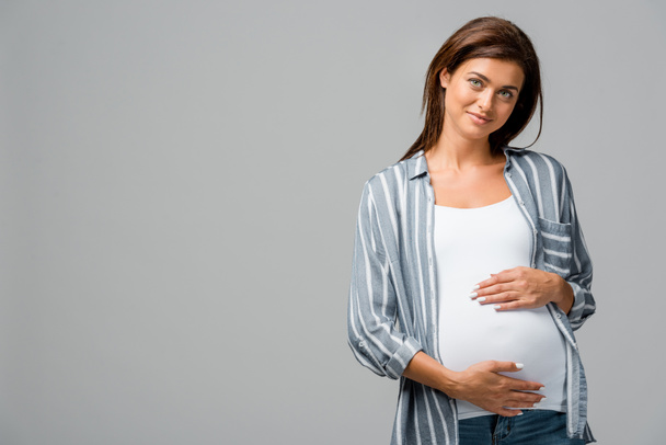 beautiful smiling pregnant woman touching tummy isolated on grey - Фото, зображення