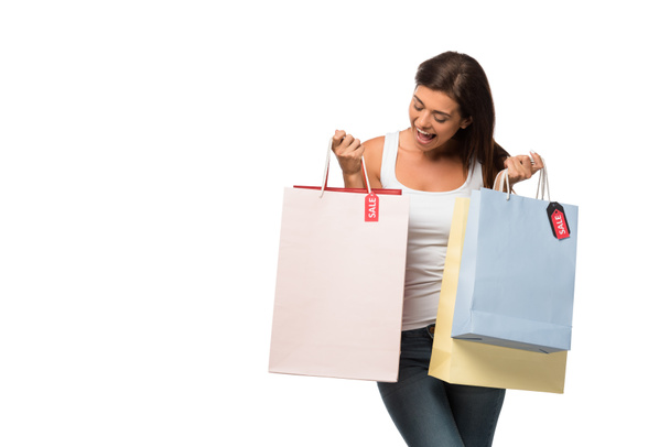 fröhliches Mädchen mit Einkaufstaschen mit Verkaufsschildern, isoliert auf weiß - Foto, Bild