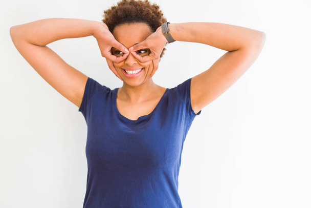 Gyönyörű fiatal afroamerikai nő mosolyogva bízik a kamera átnézett ujjaival, mint szemüveg - Fotó, kép