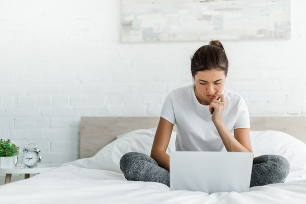beautiful pensive girl using laptop in bed in the morning  - Foto, afbeelding