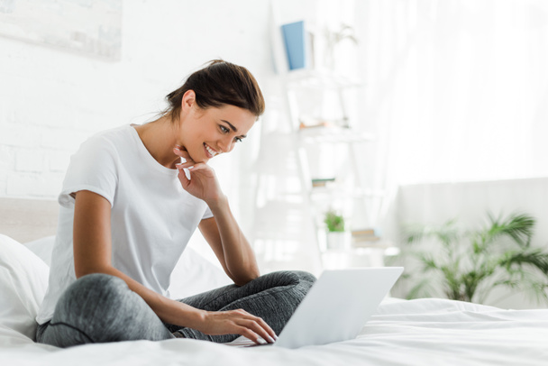 beautiful happy girl using laptop in bed in the morning  - 写真・画像