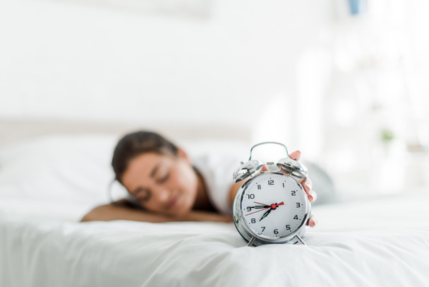 selective focus of sleeping woman with alarm clock on bed  in the morning - Foto, Imagem