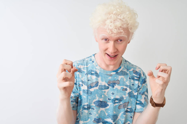 Joven hombre rubio albino con camiseta casual de pie sobre un fondo blanco aislado celebrando loco y sorprendido por el éxito con los brazos levantados y los ojos abiertos gritando emocionados. Concepto ganador
 - Foto, imagen