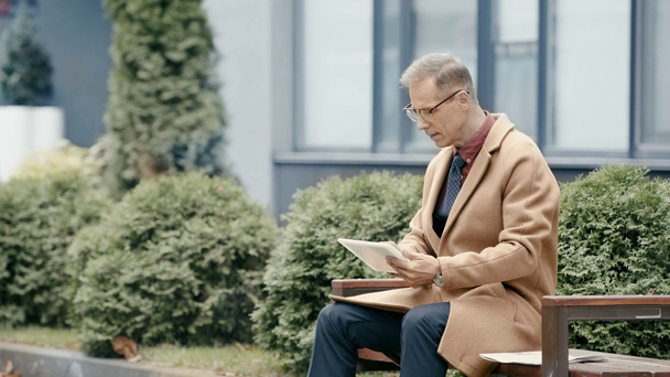 красивий бізнесмен в пальто з використанням цифрового планшета
  - Кадри, відео