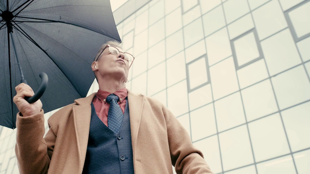 Geschäftsmann hält Regenschirm, tanzt, hört Musik  - Filmmaterial, Video