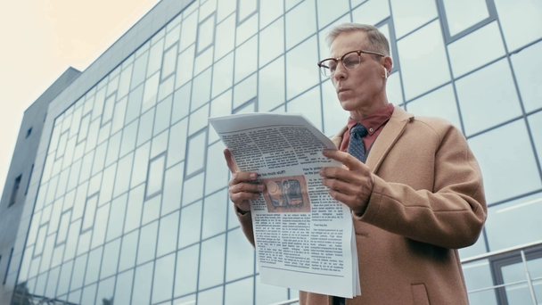 nízkoúhlý pohled obchodníka v kabátě čtení novin  - Záběry, video