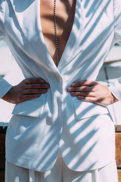 cropped view of woman in white suit posing with hands on hips outside  - Foto, imagen