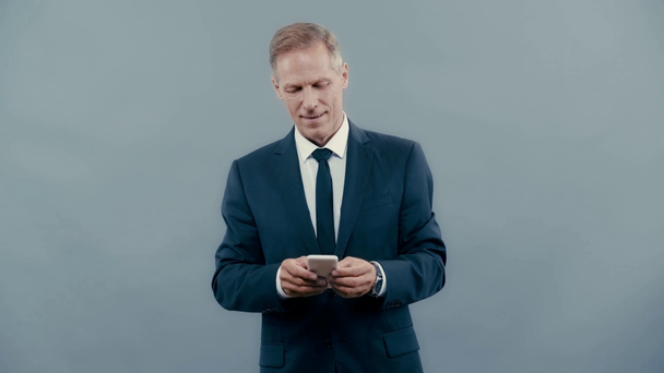 businessman in suit smiling and using smartphone  - Metraje, vídeo