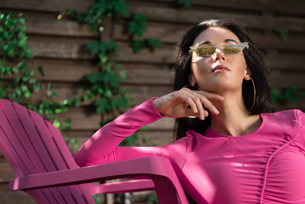 atrakcyjna kobieta w sukience i okularach przeciwsłonecznych poza  - Zdjęcie, obraz