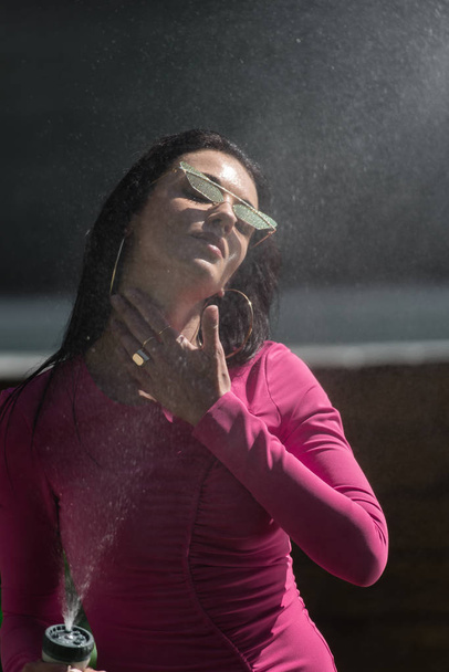atractiva mujer en vestido y gafas de sol posando con manguera de agua exterior
  - Foto, imagen