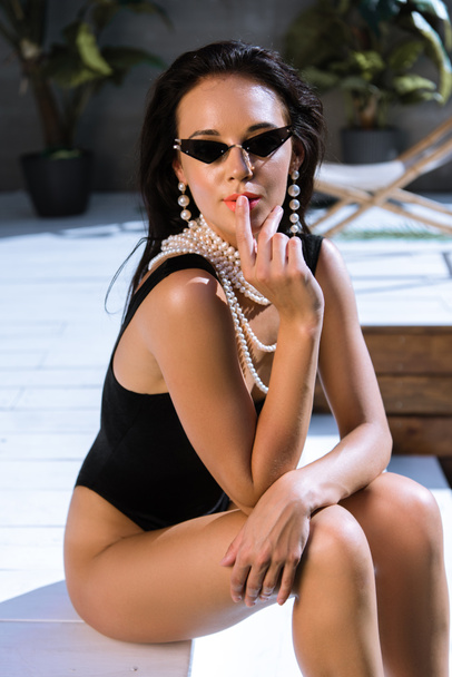 attractive woman in black swimsuit and sunglasses posing outside  - Fotografie, Obrázek