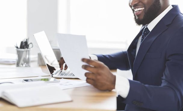 Обрізана фотографія щасливого африканського підприємця, який дивиться на документи
 - Фото, зображення
