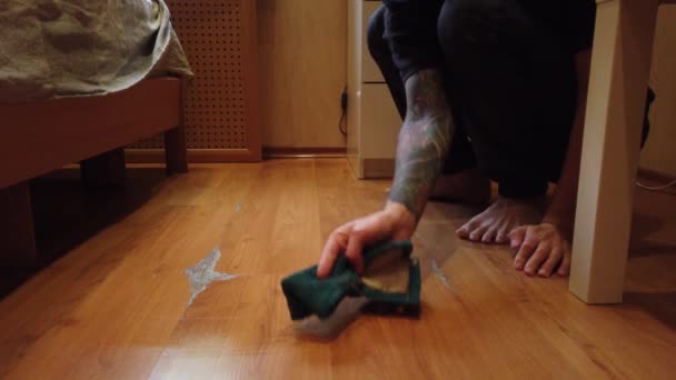 junger Mann wäscht Fußboden zu Hause. Nahaufnahme eines Mannes, der mit einem speziellen Tuch den Schmutz vom Holzboden wischt. - Filmmaterial, Video