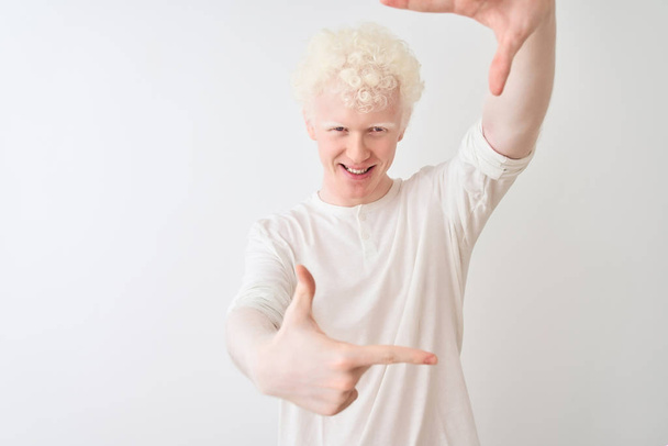 Jonge albino blonde man draagt casual t-shirt staan over geïsoleerde witte achtergrond glimlachen maken frame met handen en vingers met gelukkig gezicht. Creativiteit en fotografie concept. - Foto, afbeelding