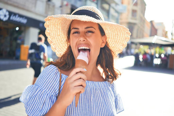 Młoda piękna kobieta jedząca rożki lodowe spacerując ulicą Teneryfy w słoneczny dzień lata na wakacjach - Zdjęcie, obraz