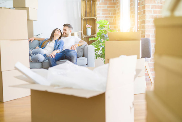 Молода пара закохалася, розслабляючись, сидячи на дивані в новому будинку, посміхаючись щаслива за переїзд в нову квартиру
 - Фото, зображення