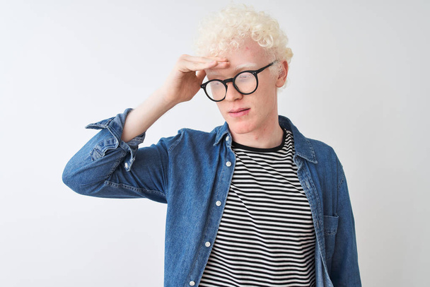 Jonge albino blonde man draagt denim shirt en bril over geïsoleerde witte achtergrond bezorgd en gestrest over een probleem met de hand op het voorhoofd, nerveus en angstig voor crisis - Foto, afbeelding