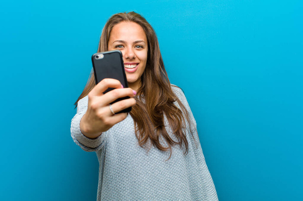 young woman with a mobile phone against blue background - Foto, Imagem