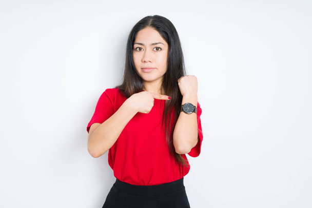 Beautiful brunette woman wearing red t-shirt over isolated background In hurry pointing to watch time, impatience, upset and angry for deadline delay - Fotografie, Obrázek