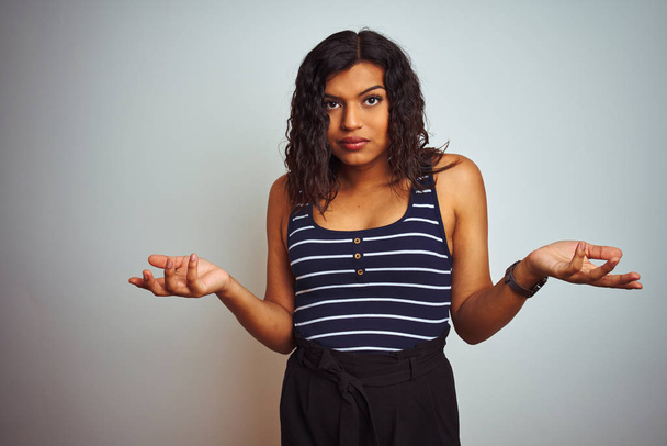 Transsexual transgender woman wearing striped t-shirt over isolated white background clueless and confused with open arms, no idea concept. - Photo, Image