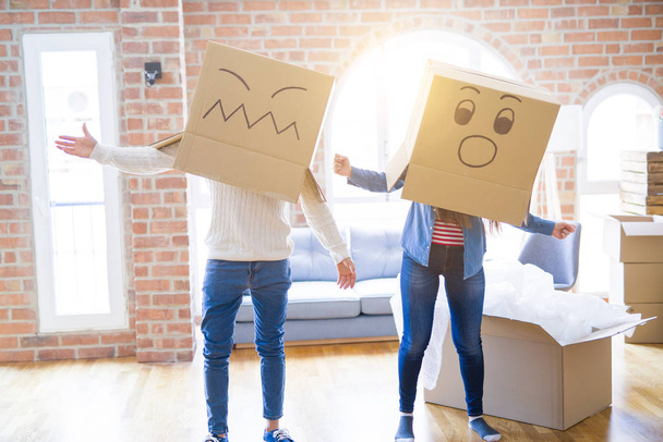 Çılgın çift kafa üzerinde komik yüzler ile kutuları giyiyor, yeni bir eve taşımak için mutlu eğlenceli - Fotoğraf, Görsel