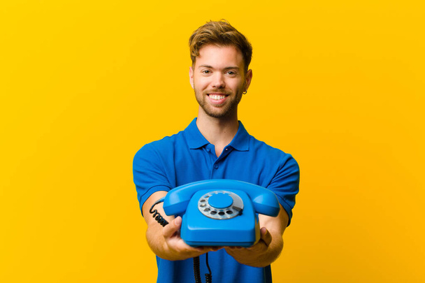 young man with a telephone against orange background - Fotoğraf, Görsel
