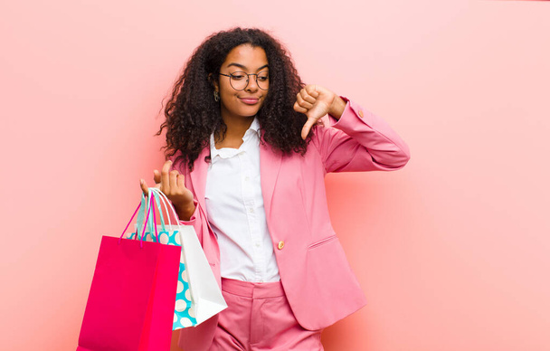 young black pretty woman with shopping bags against pink wall background - Photo, Image