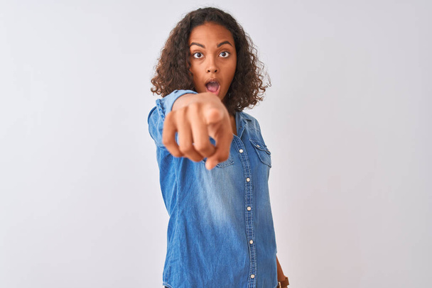 Young brazilian woman wearing denim shirt standing over isolated white background pointing displeased and frustrated to the camera, angry and furious with you - Фото, изображение